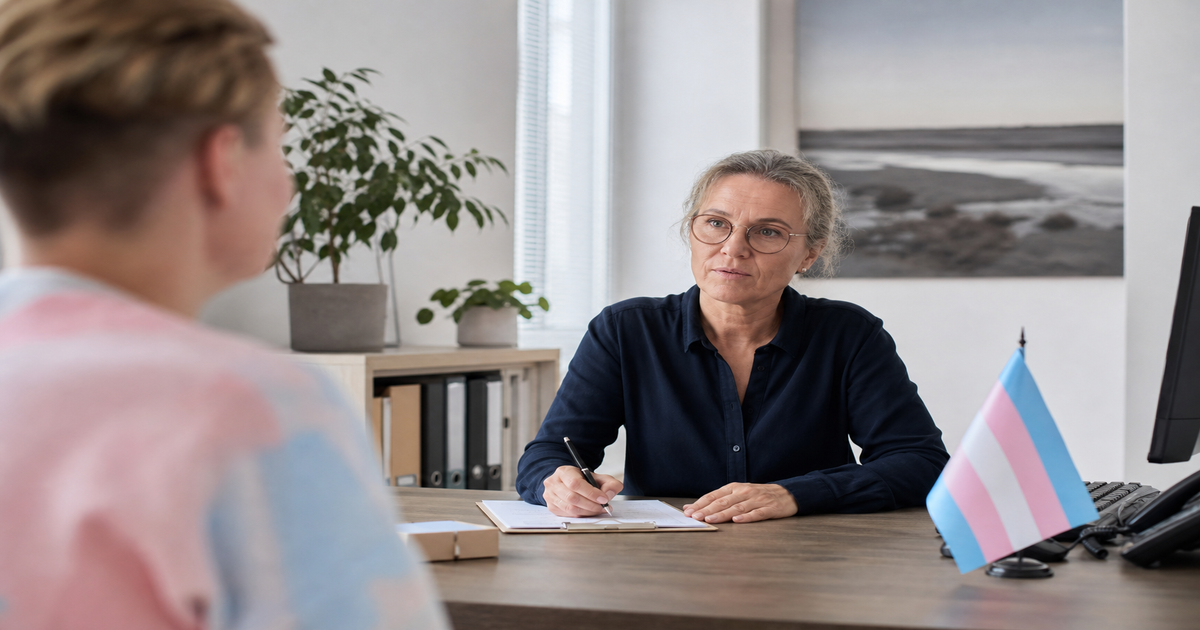 Consult in een Nederlandse genderkliniek: een behandelaar maakt aantekeningen terwijl de transgendervlag op het bureau staat.
